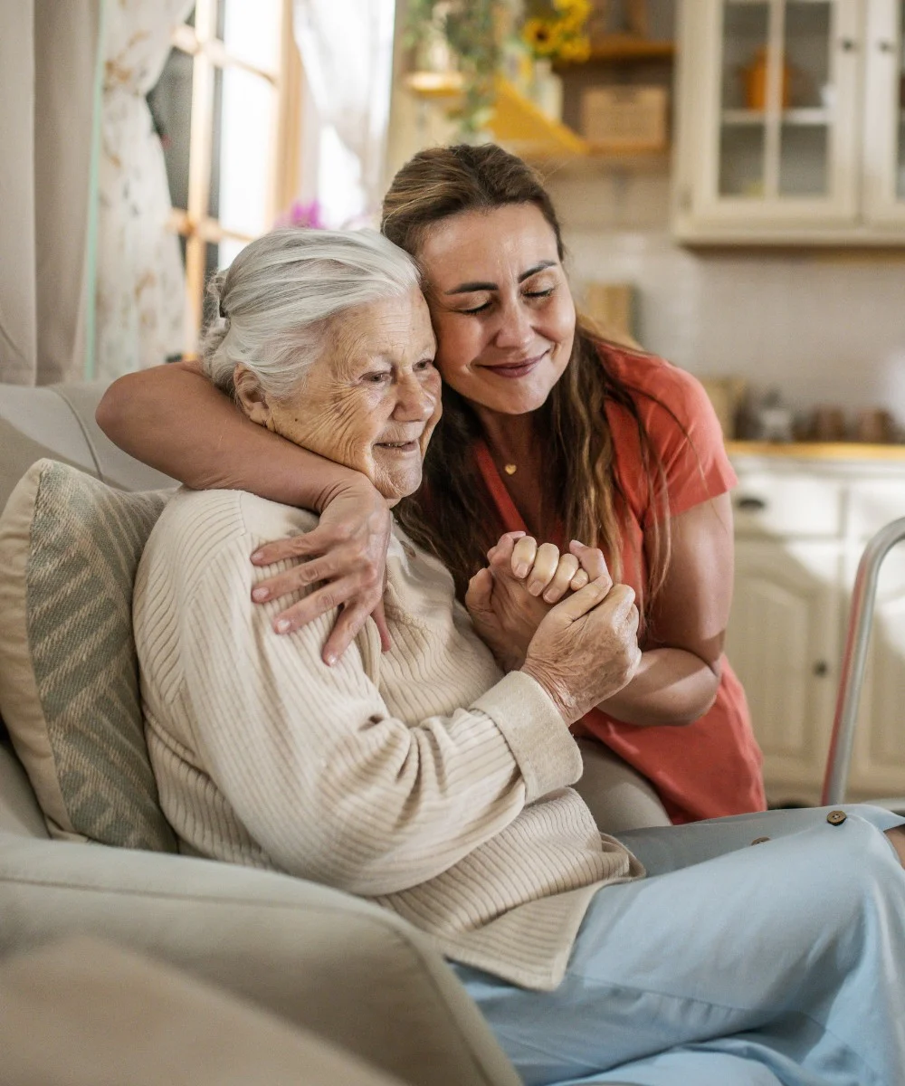 Caregiver hugging senior woman in armchair - Personal Care in Glen Ellyn. Il